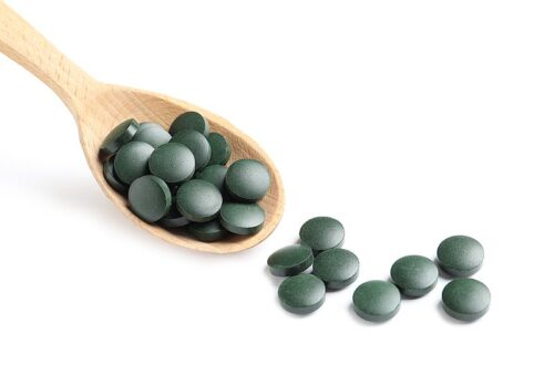 Spirulina Tabletten Pressling auf einem Holzlöffel