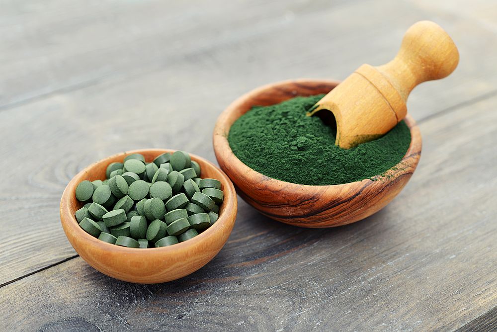 Chlorella Pulver und Presslinge in zwei Schalen zum Einnehmen